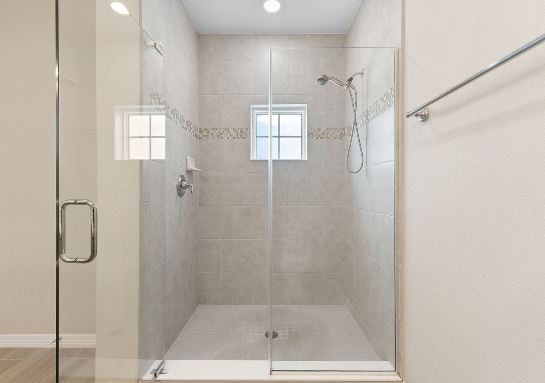 Saltwater & Sunsets- Step into your beautifully tiled walk-in shower, featuring a sleek glass enclosure and modern handheld showerhead for your refreshing daily routine.