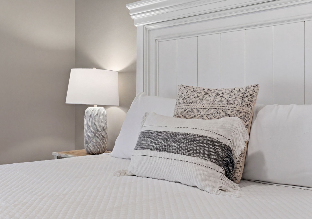 Turtles Nest- Sink into crisp linens and plush pillows in your serene coastal bedroom, where soft textures and calming neutrals promise peaceful nights and rejuvenating rest.