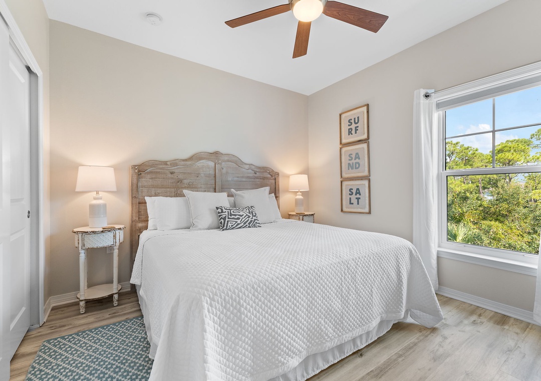 Turtles Nest- Drift off under the gentle whir of your ceiling fan in this serene coastal bedroom. Soft linens and coastal charm set the mood, while bright windows frame lush greenery outside.