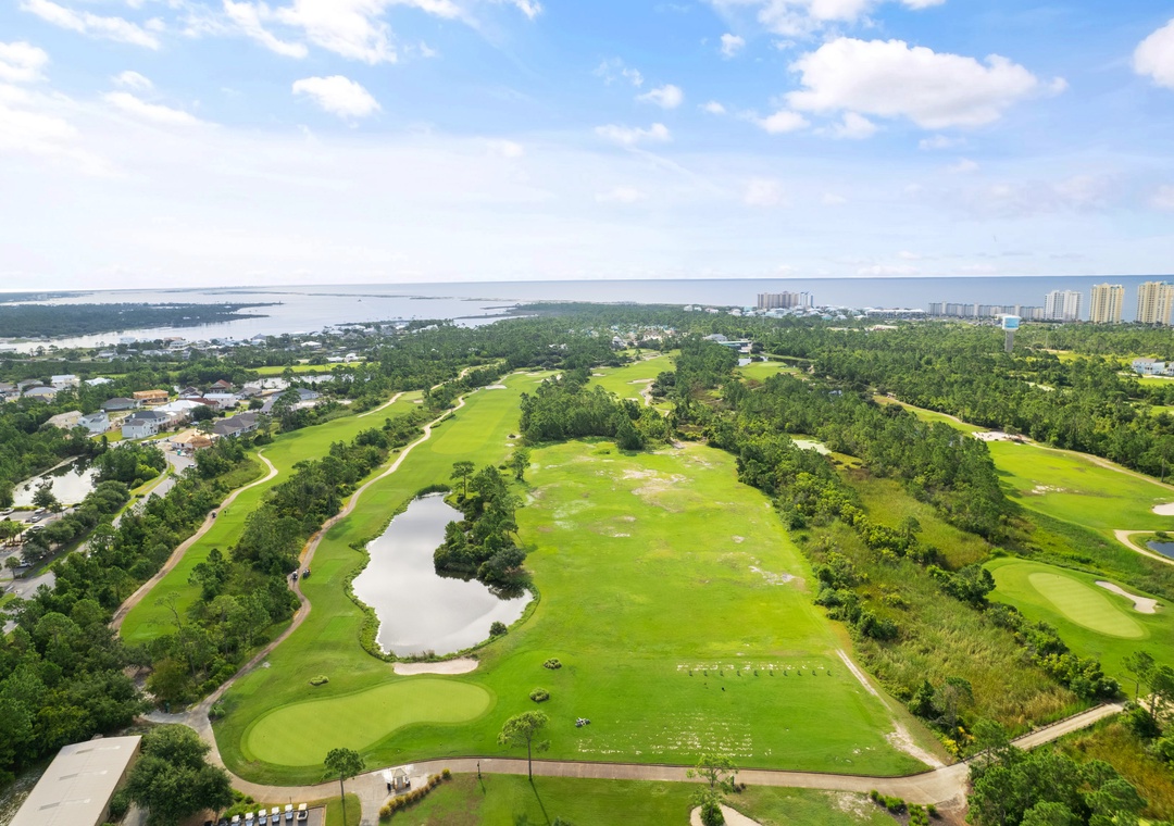 Lost Key Golf Sweeping aerial view of a championship golf course with lush fairways, pristine greens, and serene water features, bordered by coastal scenery and coastal towers in the distance.
