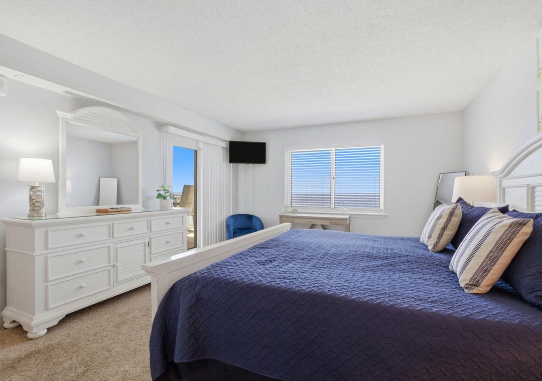 Sink into your plush king bed beneath soft navy quilts, unwind with a show, and wake to gentle sunlight streaming through plantation shutters. This serene coastal retreat is yours to enjoy.
