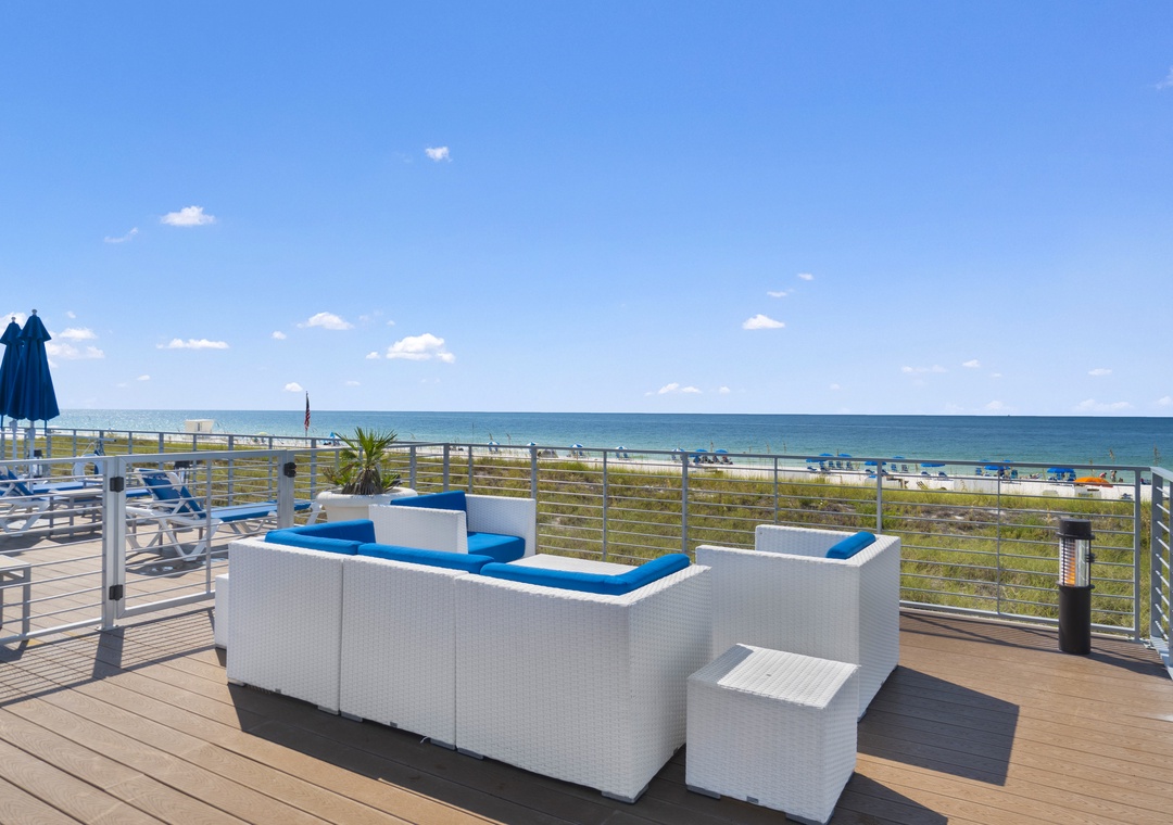 The Lost Key Beach Club A beachfront deck terrace overlooking the shoreline, featuring modern white wicker seating with bright blue cushions and direct beach access just steps away.