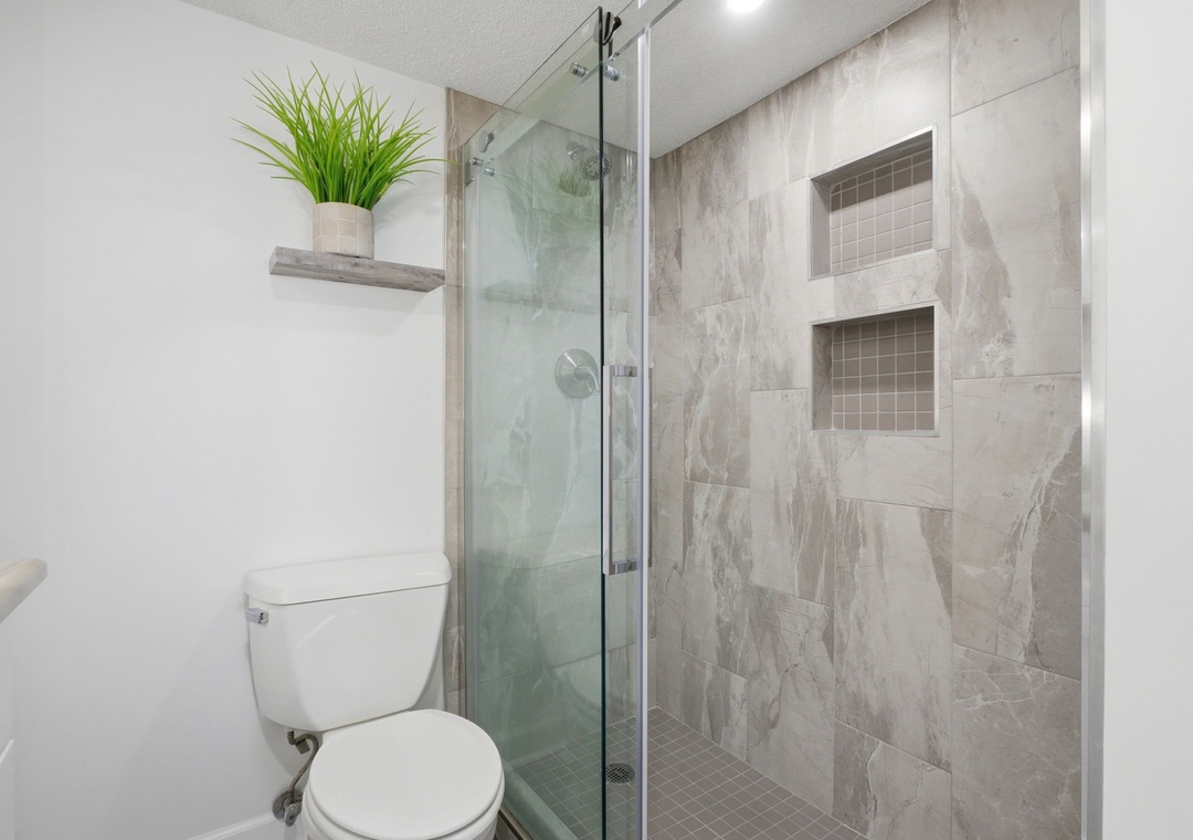 Your private bathroom features a sleek walk-in shower with elegant tile work and thoughtful built-in storage niches for your convenience.