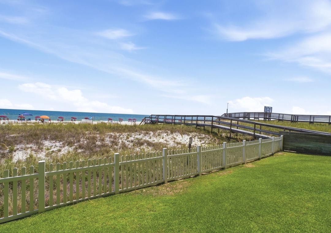 Ocean Breeze W 105-Beach access walkway leading to the sandy shoreline with colorful umbrellas dotting the coast, providing a perfect seaside setting for sunny days.