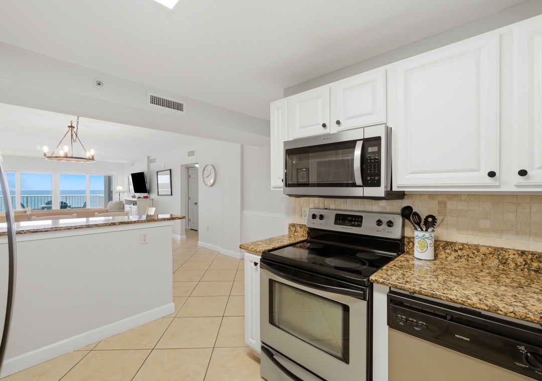 Sandy Key 318- Your kitchen features full-size appliances, granite counters, and crisp white cabinetry—all with stunning ocean views framing the open living space beyond.