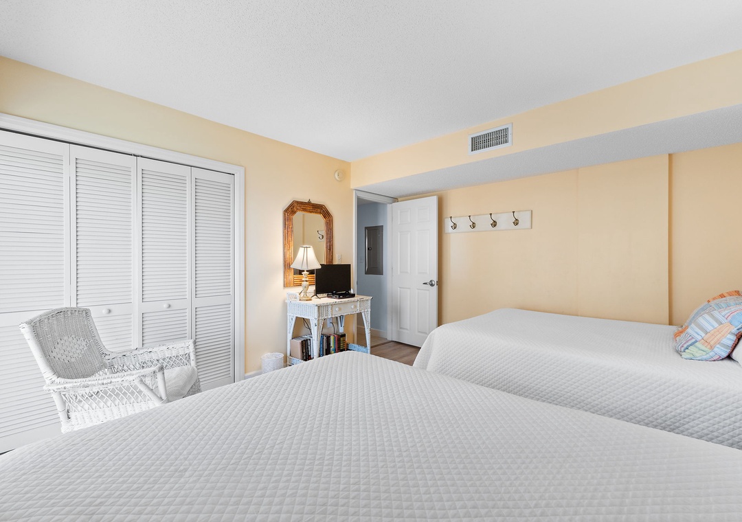 Sandy Key 338- Settle into your bright, airy bedroom with two spacious beds dressed in fresh linens. Soft natural light, tasteful coastal touches, and a cozy wicker chair invite you to unwind after a day of exploring.