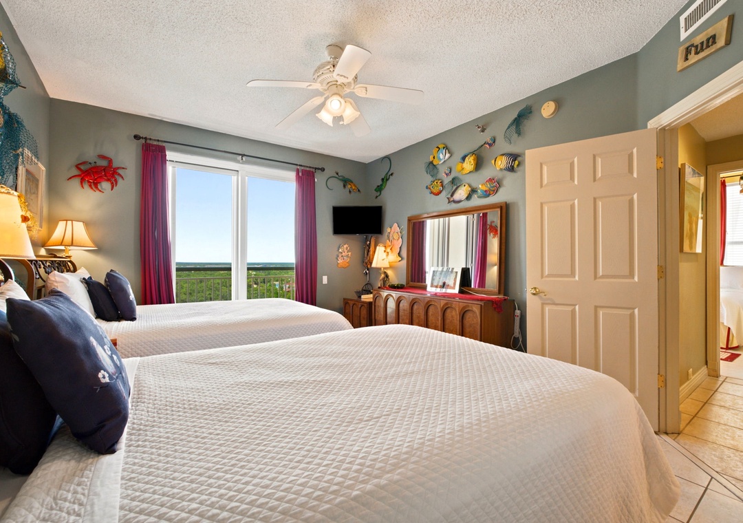 Beach Colony W13A- Rest well in this playful bedroom where tropical décor meets coastal charm. Two plush beds offer space for everyone, while your window frames endless marsh views.