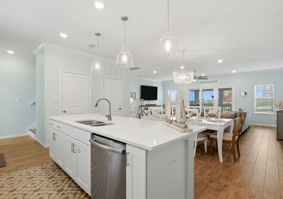 Cook and gather in your bright coastal kitchen where pendant lights sparkle above the island and windows frame views perfect for morning coffee or sunset cocktails.