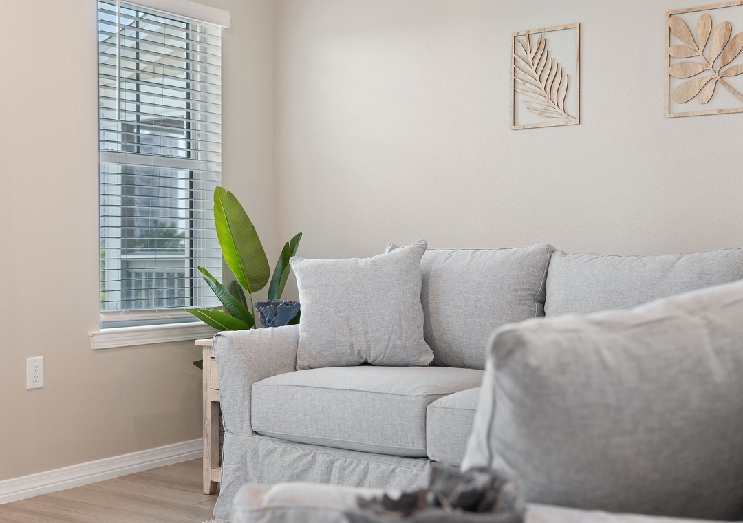 Saltwater & Sunsets- Sink into plush cushions and unwind in your serene living space, where natural light streams through the window and gentle botanical touches invite calm moments of relaxation.