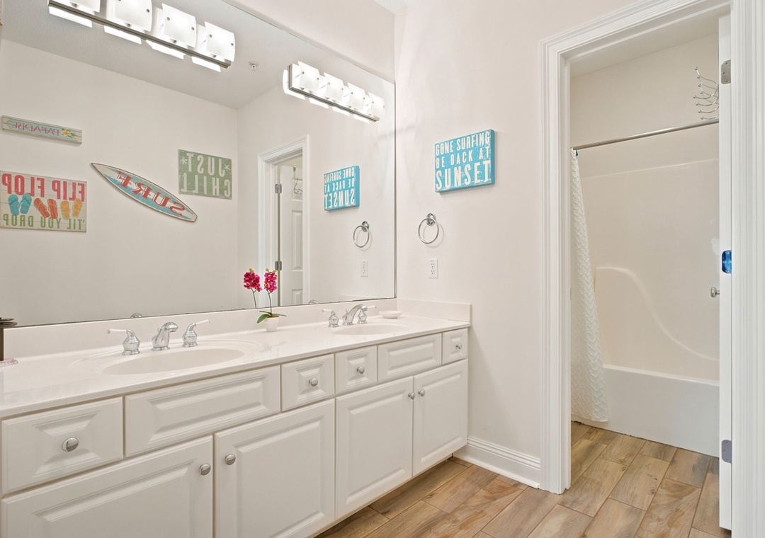 Step into your bright, beachy bathroom where playful coastal signs and dual vanities make morning routines feel like vacation. Fresh towels and beach vibes await your arrival.