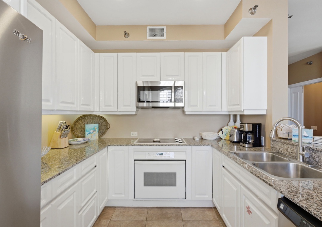 Beach Colony T PH1D- Step into your fully equipped kitchen with modern appliances, spacious granite counters, and sleek white cabinetry—perfect for preparing meals during your stay.
