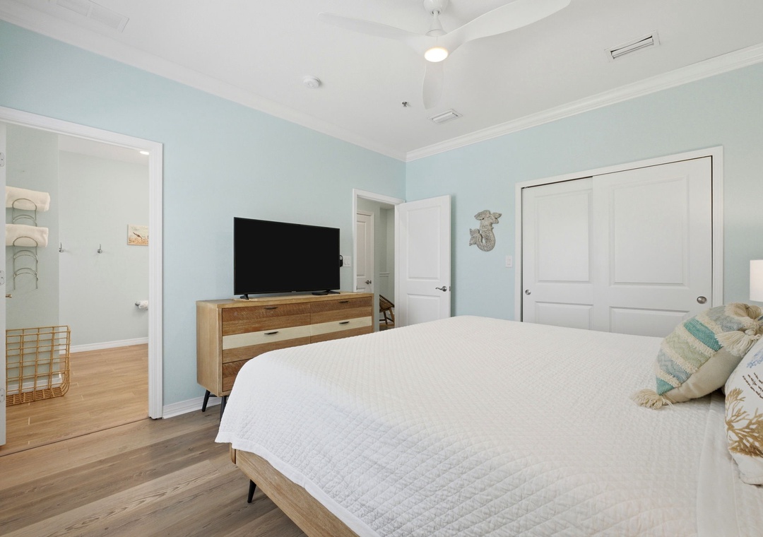 Drift off in this serene coastal bedroom with calming aqua walls, crisp white linens, and a ceiling fan to keep you cool. Your TV and ensuite bathroom ensure comfort and privacy during your stay.