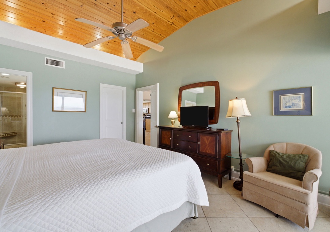 Shipwatch D803- Rest easy in your serene bedroom with soaring pine ceilings, plush bedding, and a cozy reading chair. Soft lighting and calming tones invite you to unwind after your day.