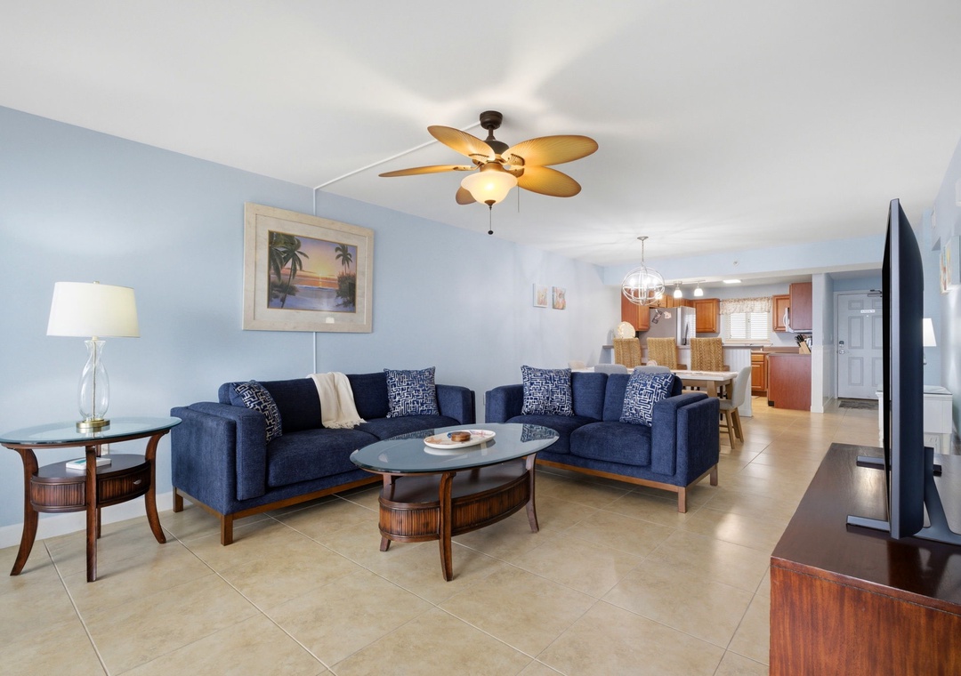 Sandy Key 637- Step into your spacious living room with soothing coastal tones, plush navy seating, and ceiling fan above. The open layout flows seamlessly into the fully equipped kitchen, perfect for relaxing after exploring.