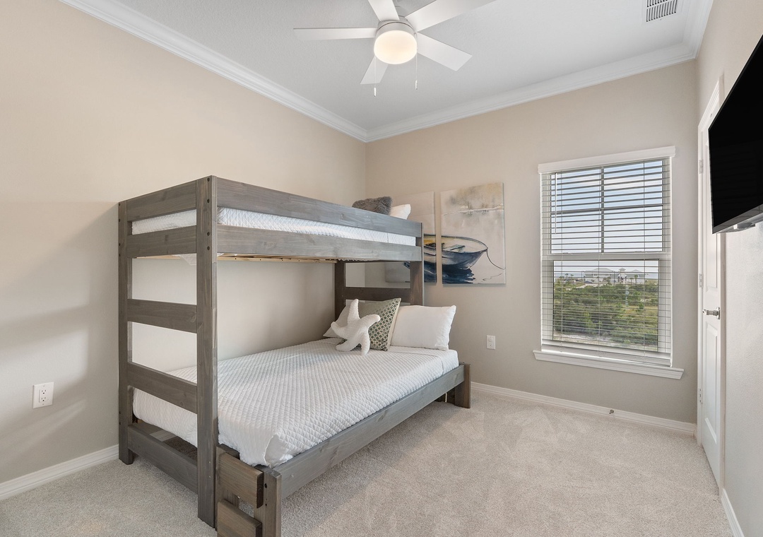 Saltwater & Sunsets- Relax in this cozy bedroom featuring comfortable bunk beds, a ceiling fan for your comfort, and coastal-themed wall art that adds a peaceful, beachy charm.