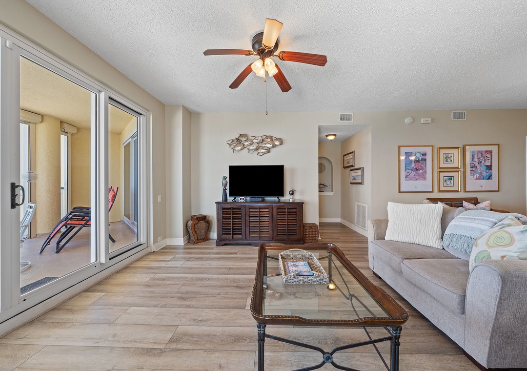 Beach Colony T15B- Settle into your spacious living room where coastal breezes drift through sliding glass doors. A ceiling fan keeps you cool as you unwind on the plush sofa, perfect for lazy afternoons or movie nights.