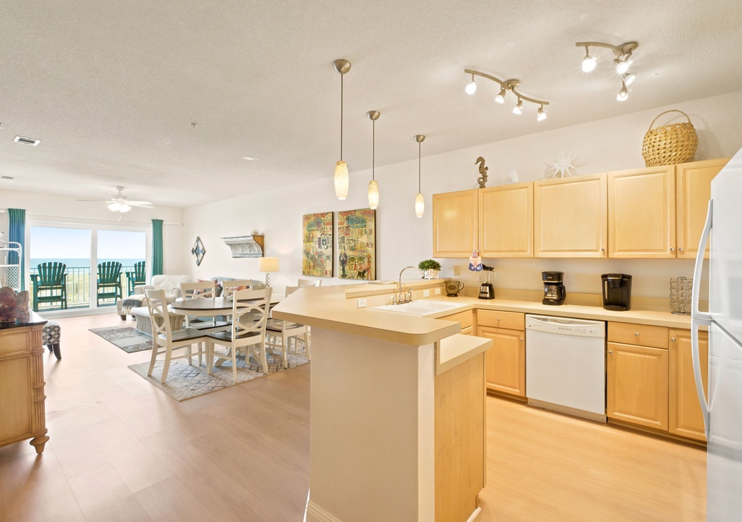 Step into your bright, open living space with a fully equipped kitchen, cozy dining nook, and inviting ocean views through expansive balcony doors. Every detail is ready for your relaxing getaway.