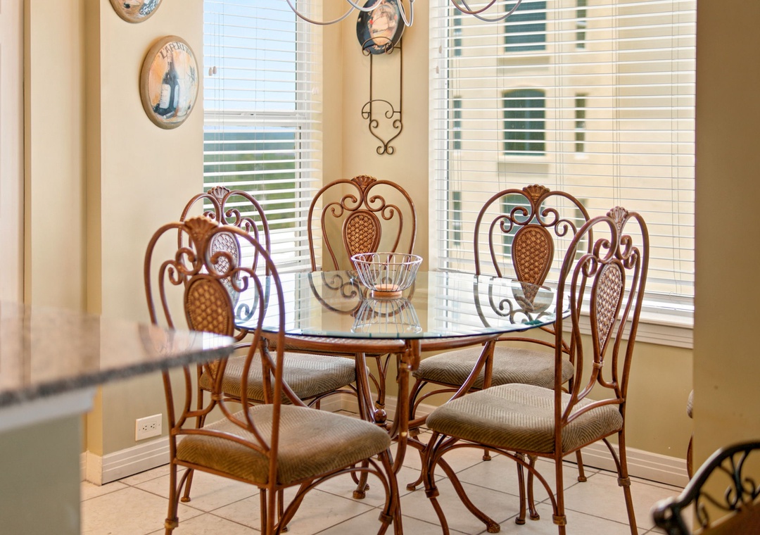 Beach Colony W13A- Gather around this charming glass-top dining table with elegant wrought-iron chairs bathed in natural light. Perfect for sharing memorable meals together.