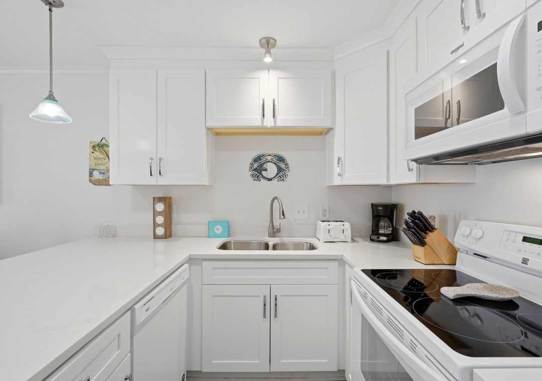 Grand Caribbean 305W- Your bright, fully-equipped kitchen features pristine white cabinetry, modern appliances, and all the essentials you'll need to whip up a delicious meal or morning coffee during your stay.