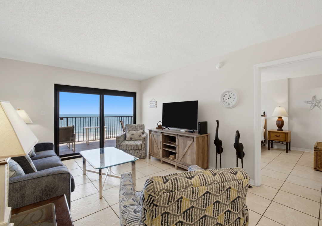 Ocean Breeze E702- Relax in this bright, coastal-themed living room with comfortable seating, a flat-screen TV, and sliding doors opening to your private balcony overlooking the ocean.