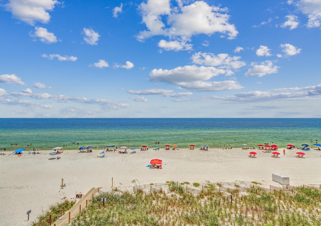 Sandy Key 411- Beautiful coastal property featuring pristine white sand beach and crystal-clear Gulf waters framed by bright summer skies.