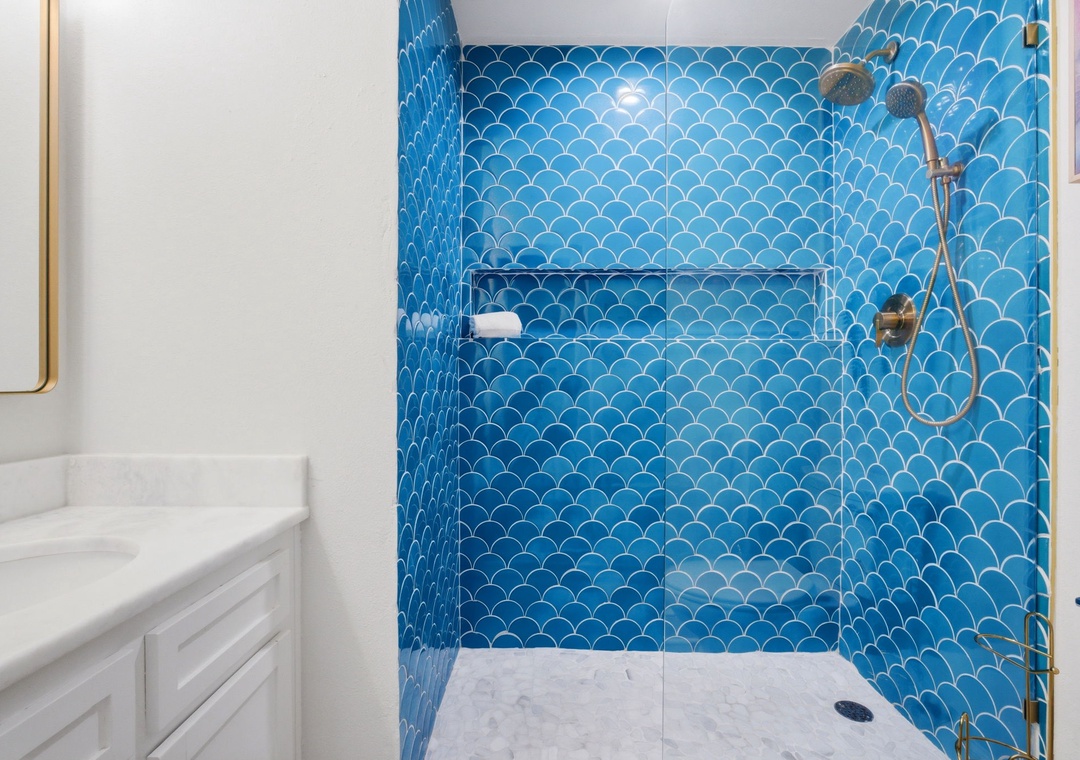 North Lost Key Landing B2- Refresh in your walk-in shower, where stunning ocean-blue scalloped tiles, brass fixtures, and a built-in niche create a spa-like retreat after a day of exploring.
