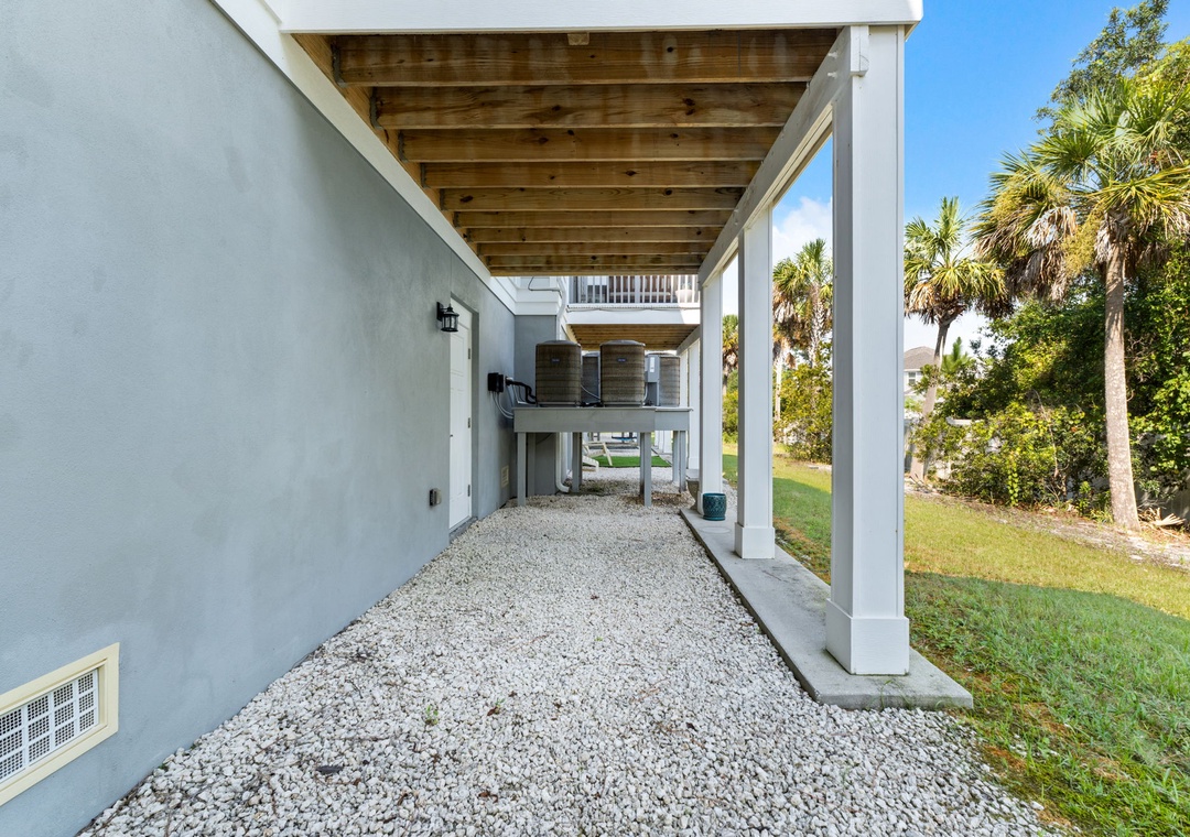 Turtles Nest- The property features an elevated structure with covered parking and storage beneath, surrounded by tropical palms and native landscaping. The architectural design provides both practical functionality & coastal charm.