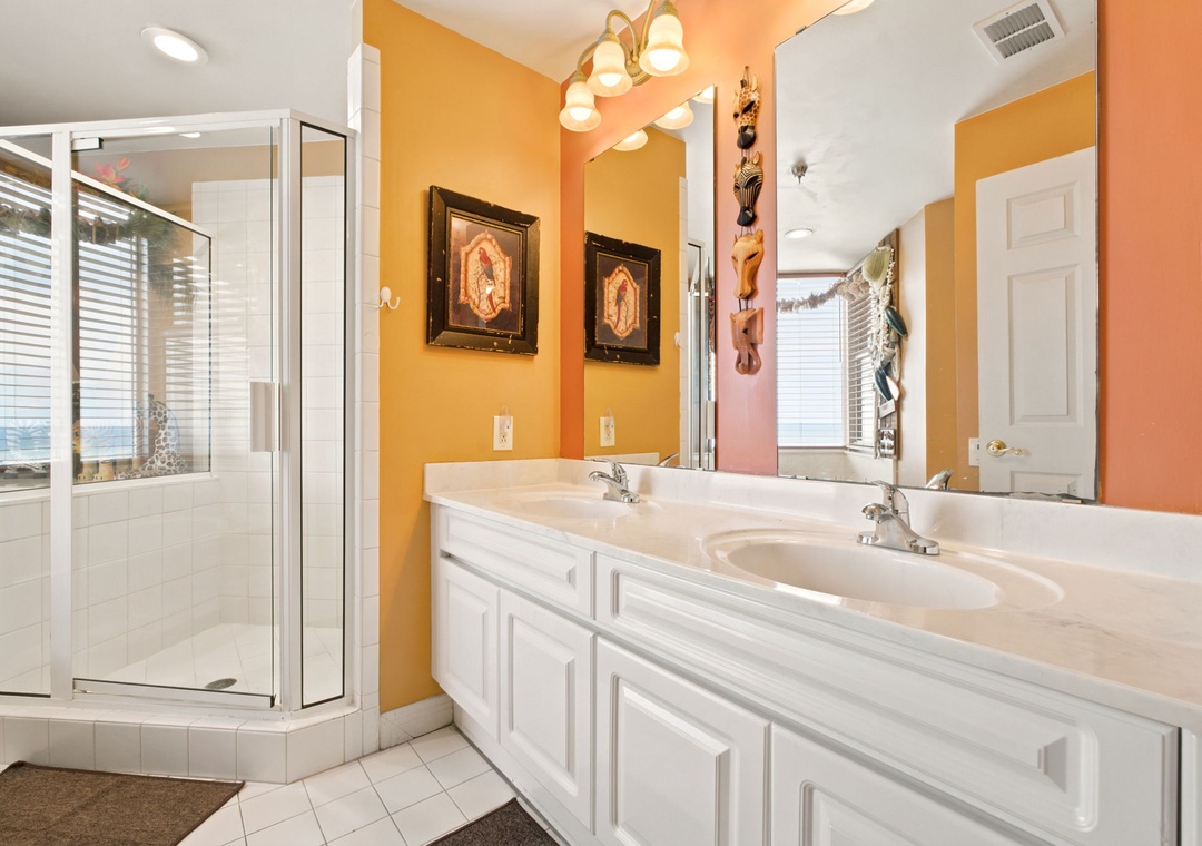 Beach Colony W13A- Refresh in your private bathroom with a spacious glass shower, dual sinks with ample counter space, and warm lighting that creates a welcoming ambiance for your morning routine.