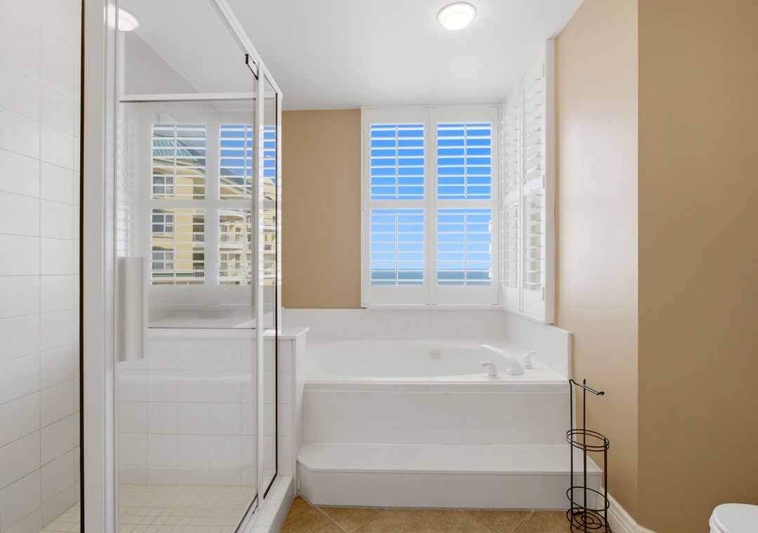 Beach Colony T PH1D- Unwind in your private bathroom with a soaking tub framed by plantation shutters and a spacious walk-in shower—your peaceful retreat after a day of adventure.