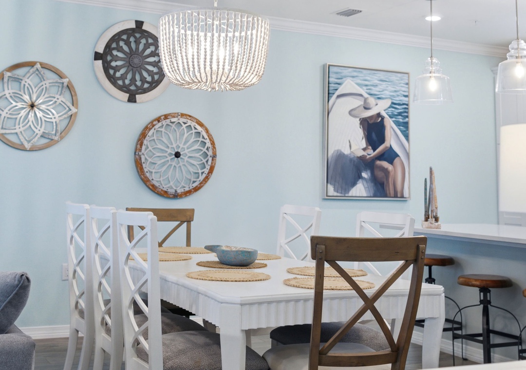 Gather around the coastal-inspired dining table, where beaded chandelier light dances across your morning coffee and laughter fills the breezy blue space.