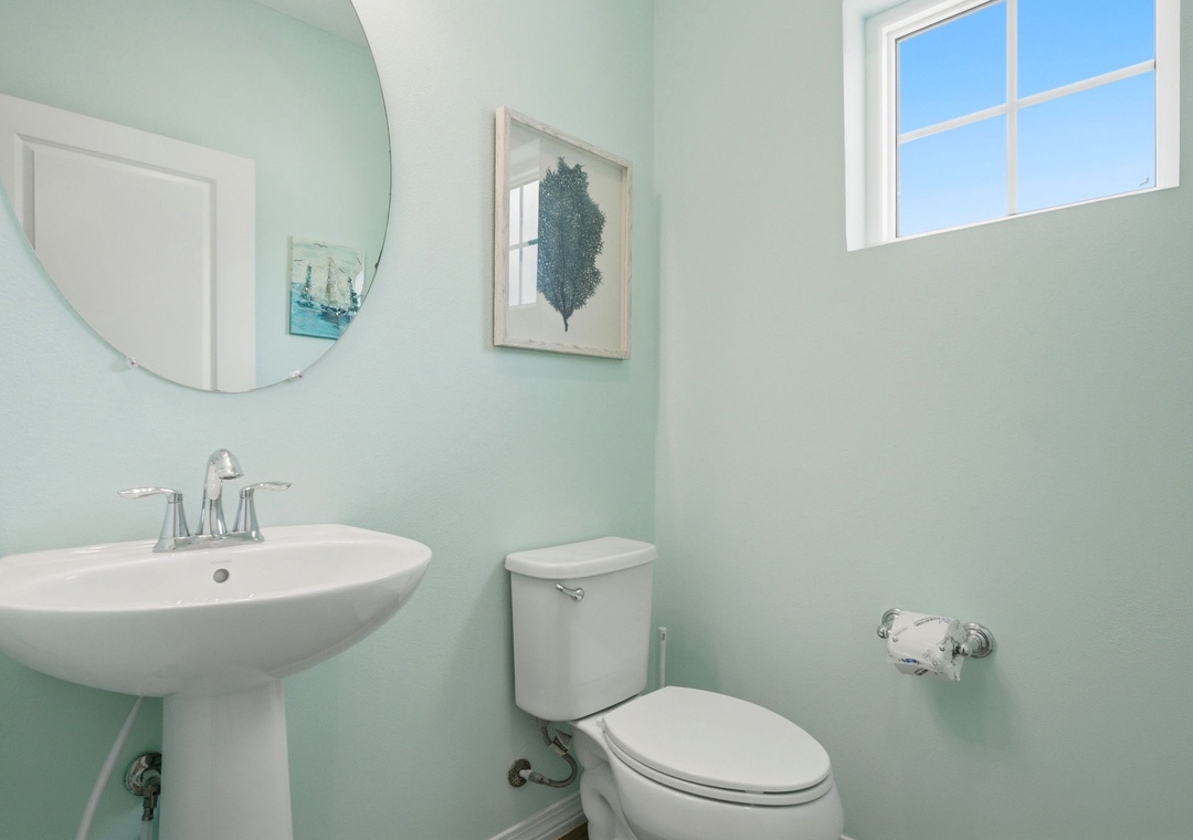 Refresh yourself in this calming powder room with soft coastal tones, a gleaming pedestal sink, and ocean-inspired art that brings a serene seaside feel to your daily routine.