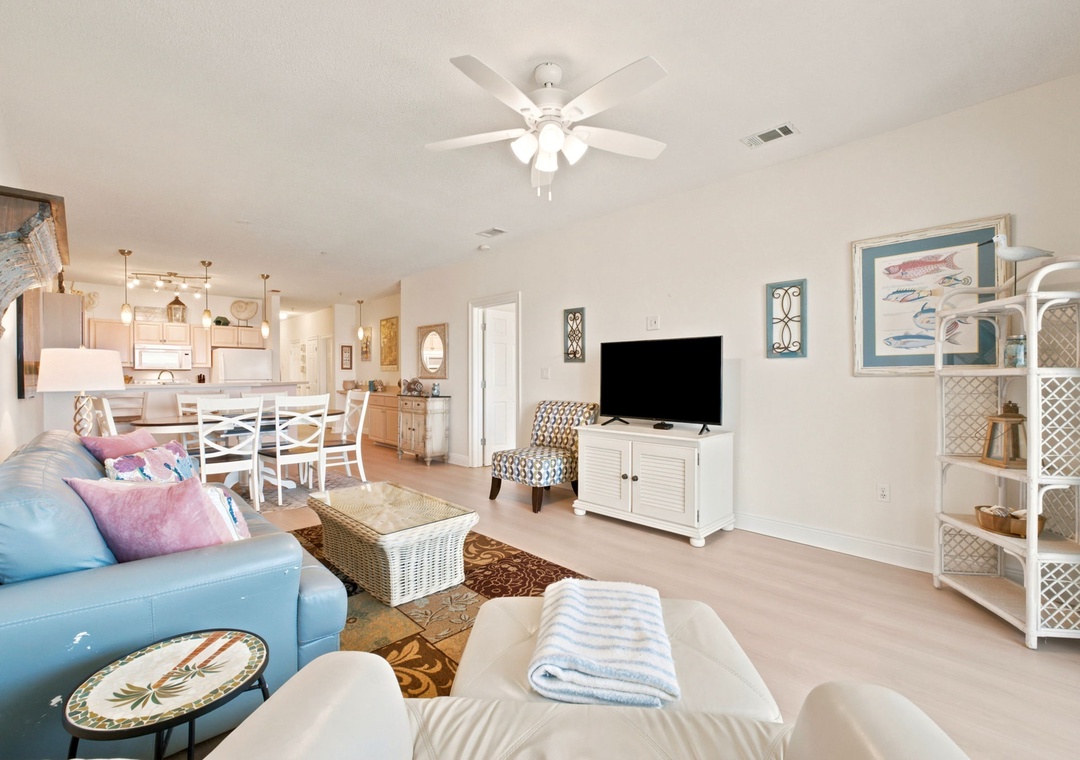 Unwind in your bright, coastal-inspired living area, complete with plush seating, ceiling fan, and entertainment center—perfect for relaxing after a day of adventure.