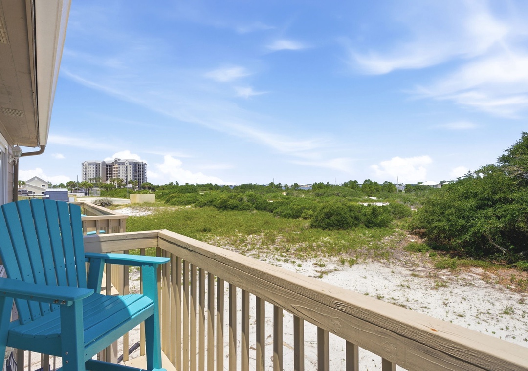 North Lost Key Landing B2- Balcony overlooks a peaceful natural landscape with coastal vegetation, sandy stretches, and distant buildings under a bright blue sky.