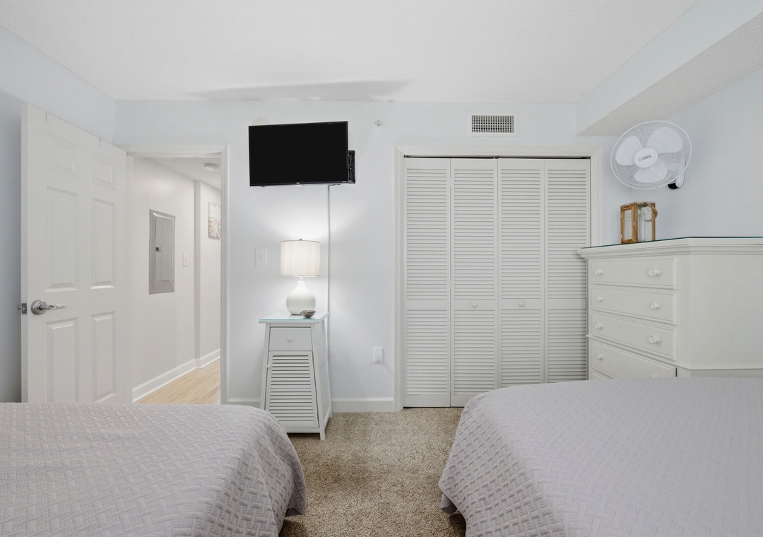 Your serene bedroom retreat features two plush beds, ample storage with louvered closets and a dresser, plus your own TV for relaxing evenings in comfort.