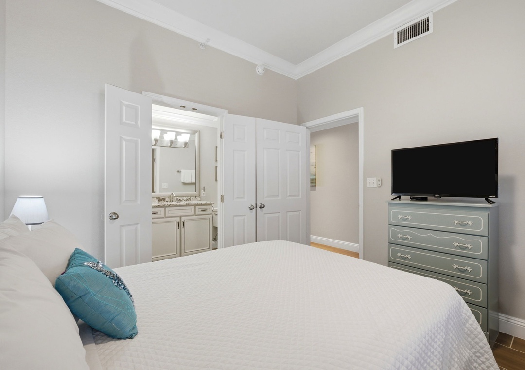 You'll rest easy in this serene bedroom, complete with a cozy bed, charming dresser, and flat-screen TV for your entertainment. The en-suite bathroom awaits just steps away.