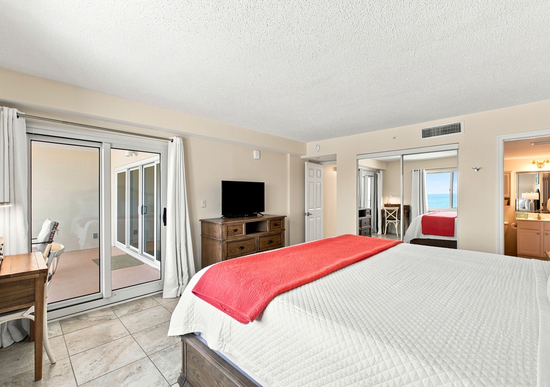 Sandy Key 411- Step into your spacious bedroom retreat with a private balcony overlooking tranquil ocean waters. The bright, open layout invites you to unwind in comfort while enjoying stunning sea views just beyond the glass doors.