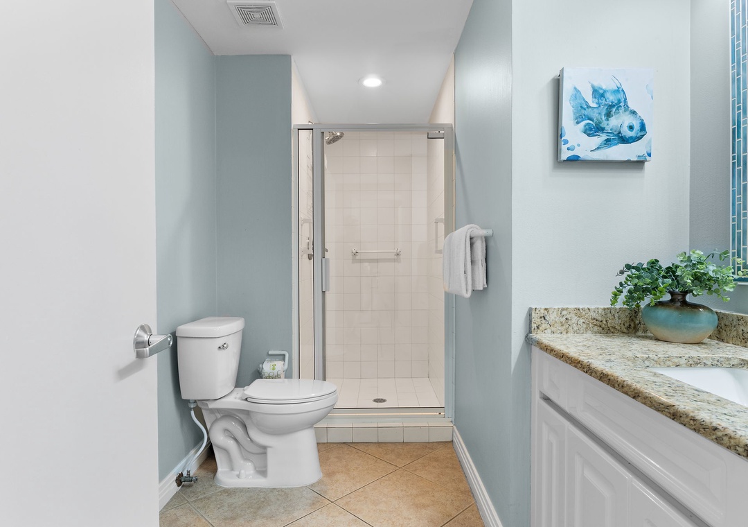 Refresh in your private bathroom with soothing coastal blue tones, a spacious walk-in shower, and clean granite countertops. Plush towels await, and cheerful artwork adds a splash of seaside charm.