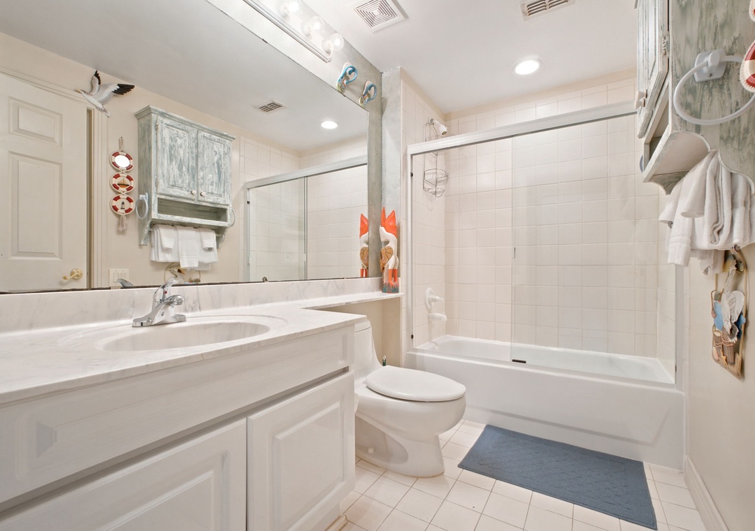 Beach Colony W13A- Your bright, spotless bathroom features dual sinks, fresh white tile, and a full tub-shower combo, with thoughtful nautical touches that capture the coastal charm.