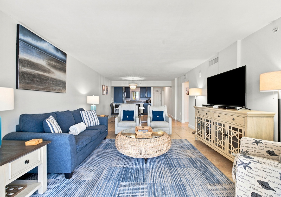 Sandy Key 411- Unwind in your bright, open living space with coastal-inspired blues and comfortable seating. You'll love the open layout that flows into the kitchen and dining area—perfect for gathering with your group.