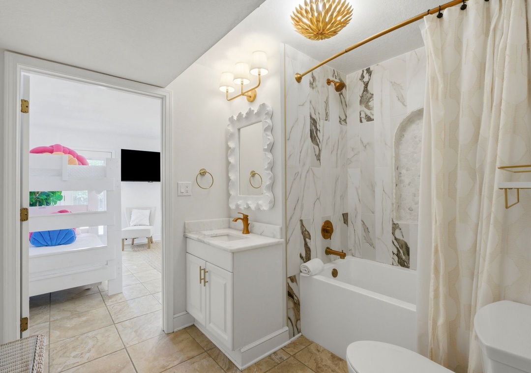 North Lost Key Landing B2- Refresh in this bright bathroom featuring elegant marble tile, gold fixtures, and a relaxing tub-shower combo with all the comforts of home.