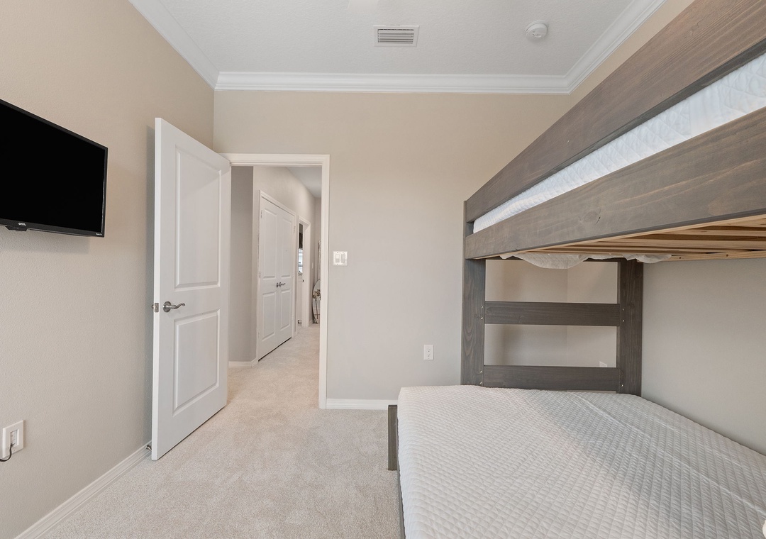 Saltwater & Sunsets- Your comfortable bunk room offers both space and privacy, with soft carpeting and a wall-mounted TV for cozy evenings after busy days exploring.