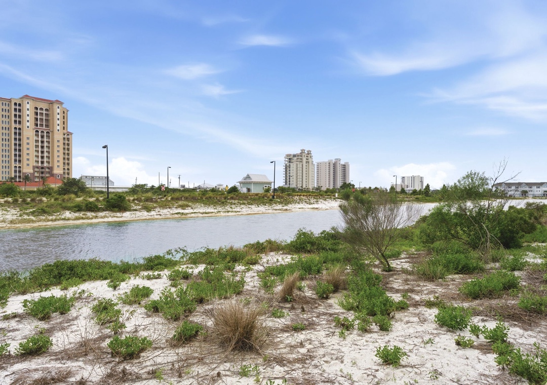 Coastal lagoon and natural dunes anchor this waterfront neighborhood, with residential towers marking the surrounding area.