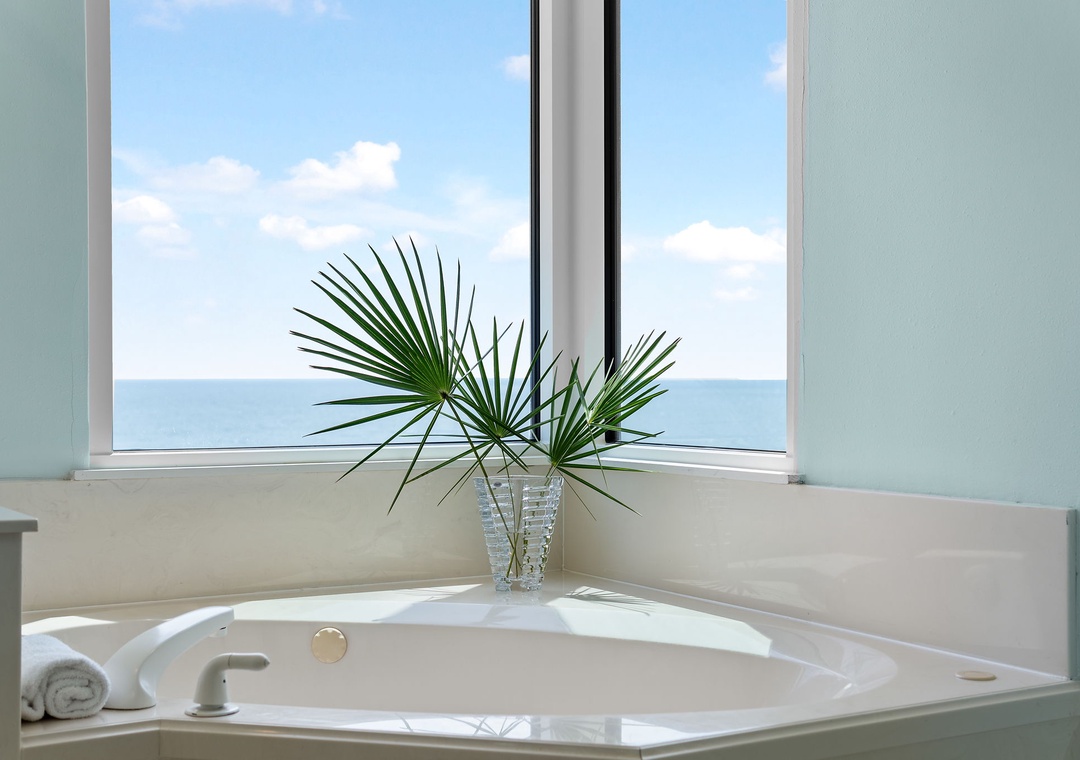 Beach Colony Tower 10C- Sink into this luxurious corner soaking tub while gazing at endless ocean views through your window—your own private sanctuary for relaxation.