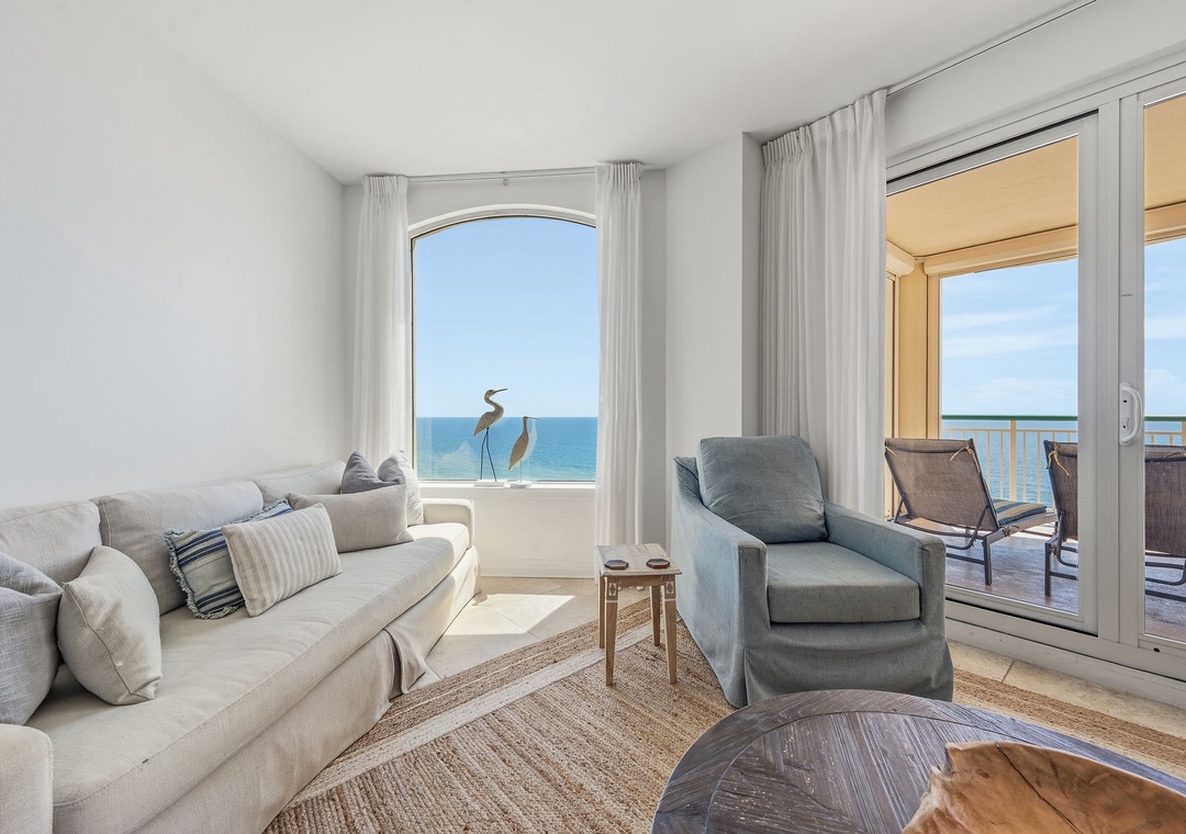 Beach Colony T14B- Sink into plush seating and gaze through panoramic windows at the sparkling sea—your serene coastal sanctuary awaits, with a private balcony just steps away.