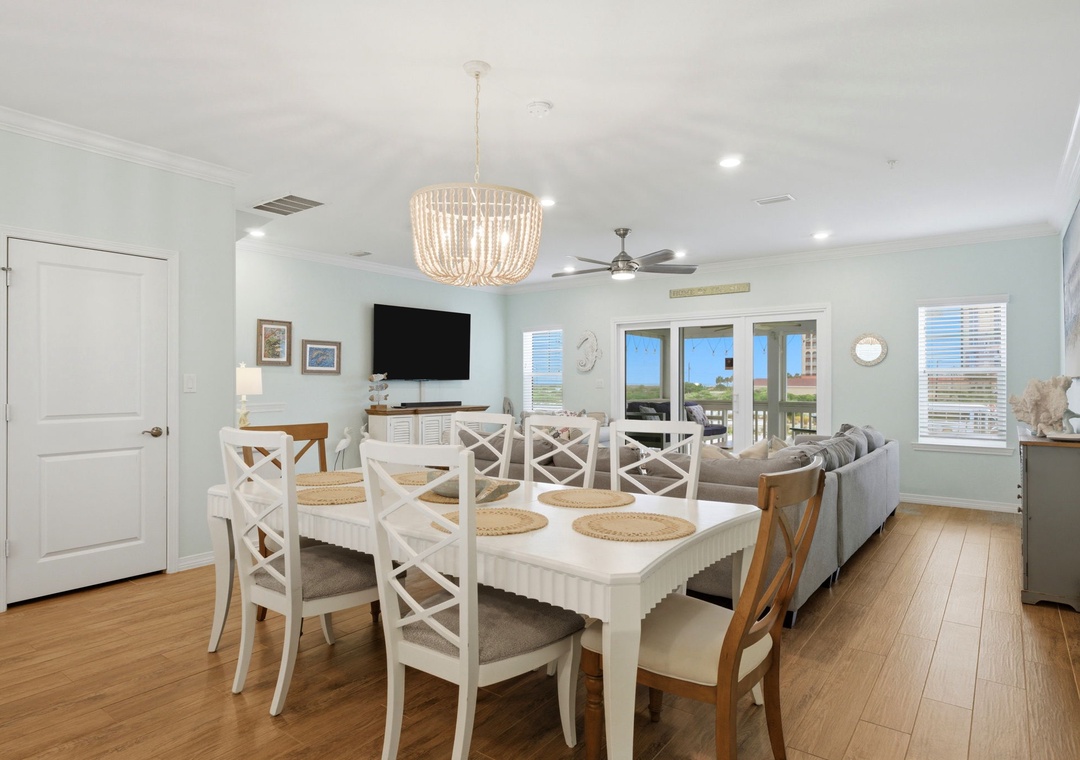 Your bright coastal retreat blends dining and lounging seamlessly under a stunning beaded chandelier. Natural light pours through wide glass doors framing serene views, inviting you to unwind in style.
