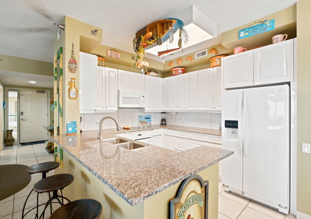 Beach Colony W13A- You'll love preparing meals in this bright, fully-equipped kitchen with granite countertops, modern appliances, and charming beach-themed touches that make it feel like home.
