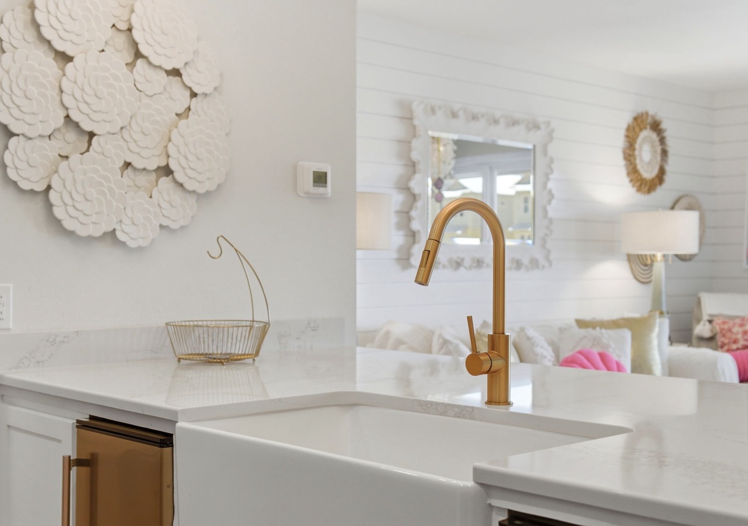 North Lost Key Landing B2- Step into your stylish kitchen where elegance meets function—crisp white counters, a gleaming gold faucet, and coastal décor invite you to cook and unwind in comfort.
