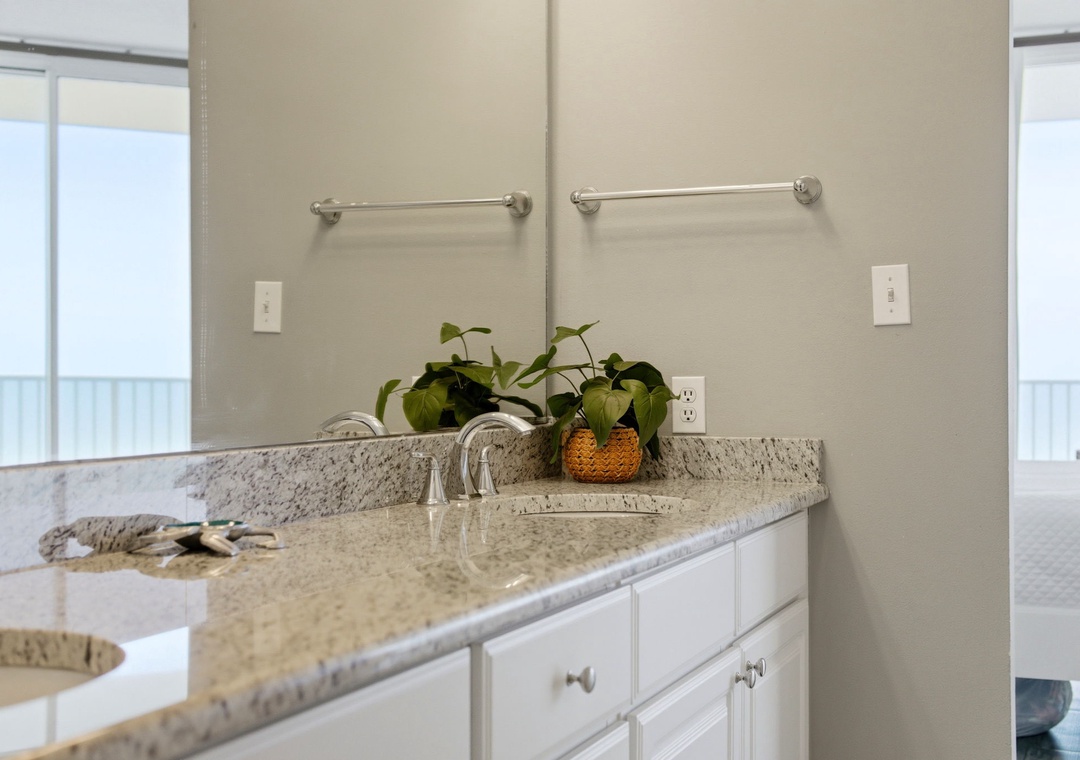 Lighthouse 418- Your spacious bathroom features a polished granite countertop, dual mirrors, and fresh greenery to brighten your stay. Natural light streams in, creating a serene space for your morning routine.