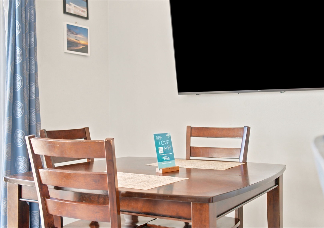 Your cozy dining area invites you to share meals together beneath warm natural light, with a flat-screen TV ready for entertainment and cheerful wall art to brighten your stay.