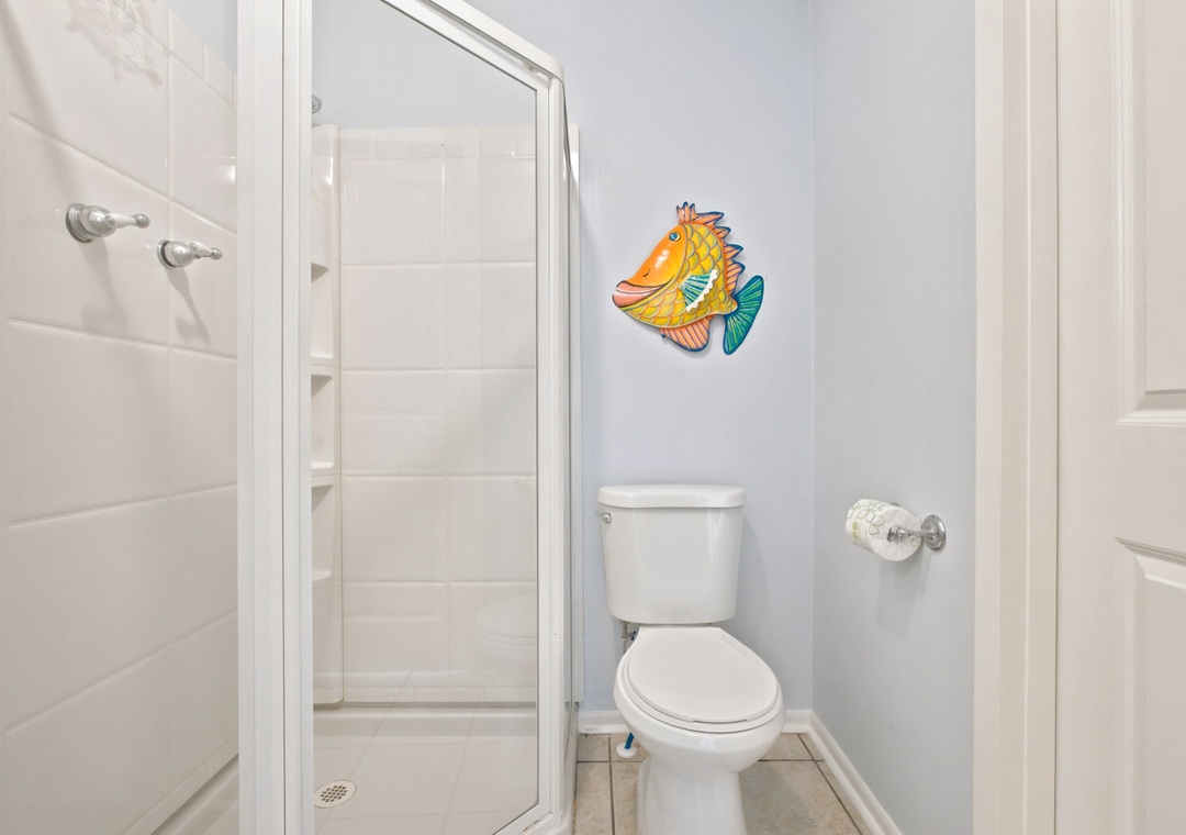 A bright, clean bathroom with a playful touch—a cheerful fish decoration adds personality to your private space. The modern shower and essential amenities ensure your comfort.